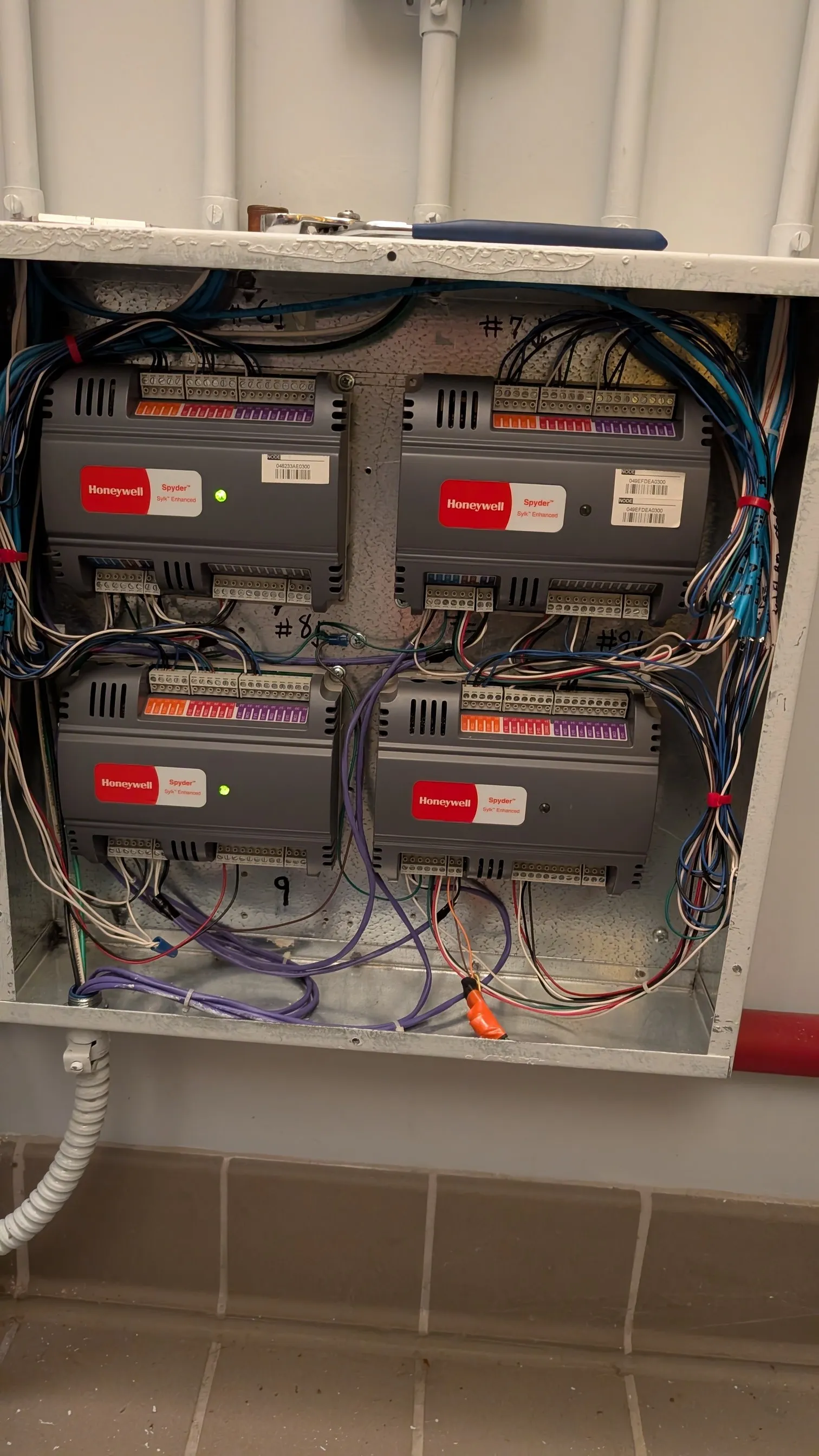 Four Honeywell Spyder Sylk Enhanced LON controllers in an equipment panel before conversion